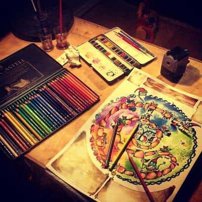 Μολύβια διαφορετικών χρωμάτων και ζωγραφισμένο χαρτί πάνω σε τραπέζι.